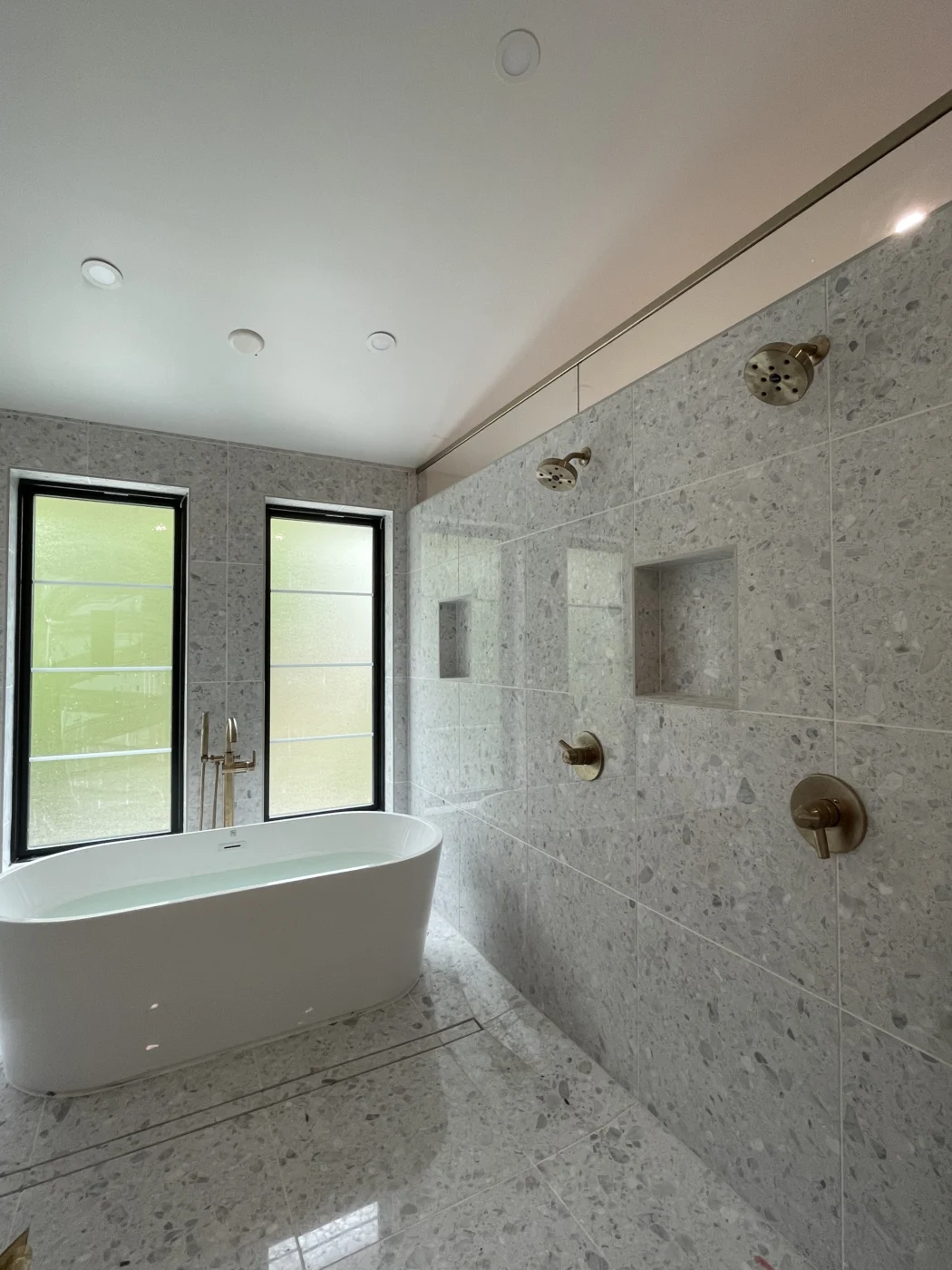 Gray tile shower with black fixtures and glass door in a completed bathroom remodel