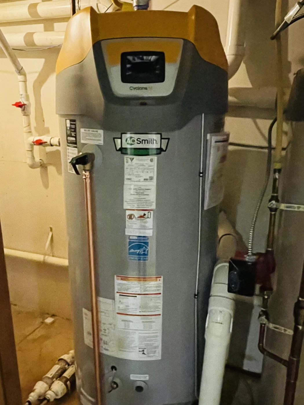 Residential water heater installed in a mechanical room with nearby plumbing connections