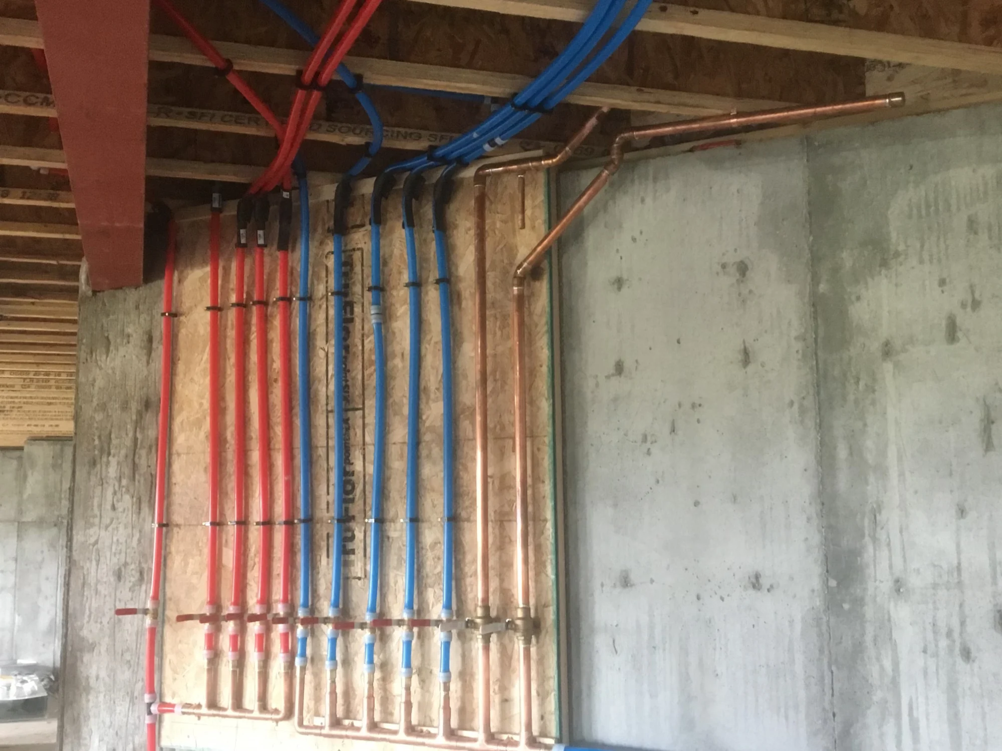 Red and blue PEX plumbing lines installed neatly along a basement wall