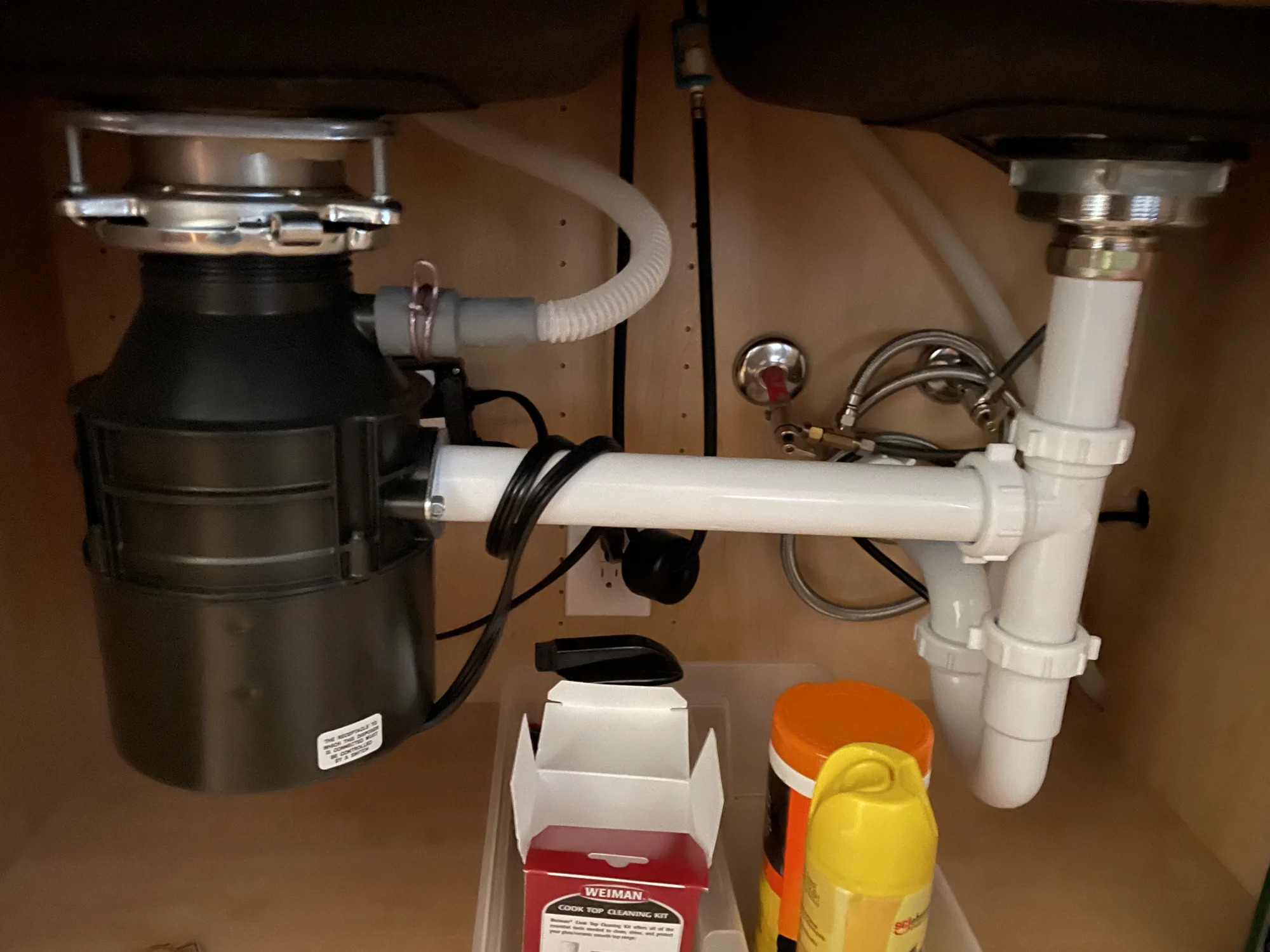 Garbage disposal and drain plumbing installed under a kitchen sink cabinet