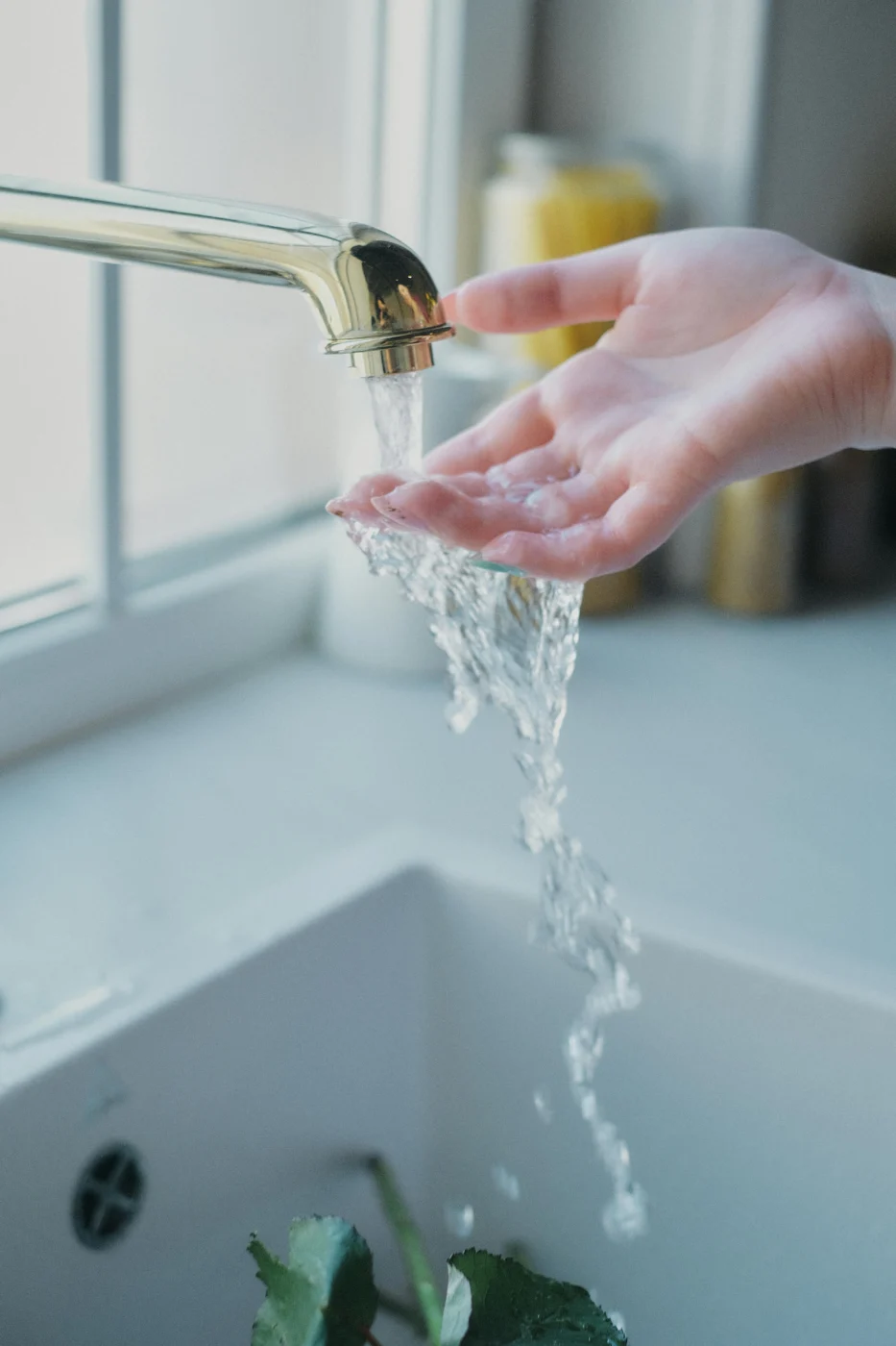 Hands rinsing under clean running water at a kitchen sink